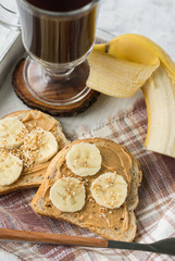 Sandwiches with peanut butter and banana and coffee close-up for breakfast