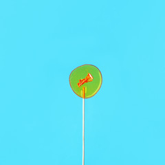 Yellow lollipop ion blue background. Girls hold hard candy caramel on stick, sweets holidays concept, copy space for text, minimal, summer creative idea - sun and blue sky