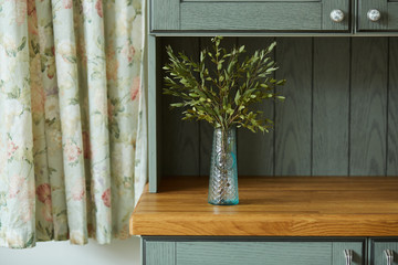 A vase with eucalyptus on a kitchen shelf