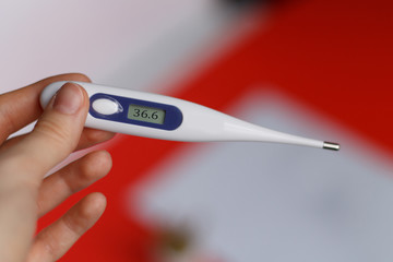 electronic thermometer in hand close up with body temperature