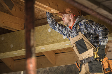 Caucasian Worker Checks Wooden Framing Of New Attic.