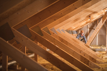 Construction Worker Insulating Attic Space Of Home. - obrazy, fototapety, plakaty