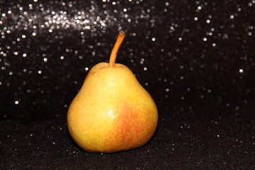 Fototapeta na wymiar Yellow pear on a shiny black background. Bright juicy fruit.
