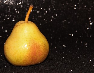 Yellow pear on a shiny black background. Bright juicy fruit.