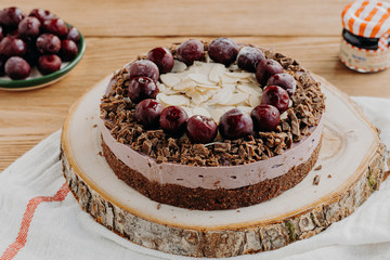 Cherry cake on a wooden background. Almonds in a raw dessert.	
