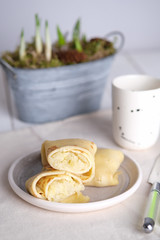Baked large pancakes with vegetable filling in the cut, on the table with a light napkin under the plate