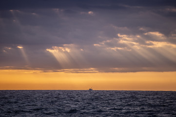 A boat in the middle of the sea. A fishing boat in the sea during the first hours of the day.