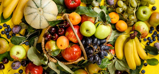 Flat-lay of fresh fruits and berries on yellow background