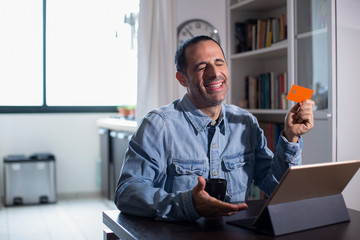 Uomo moro con camicia in jeans, fa degli acquisti via internet con la sua carta di credito
