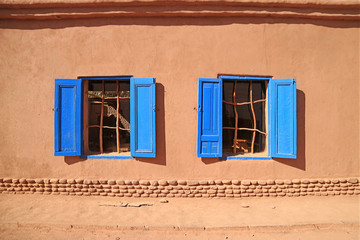 Vivid blue colored windows on brown adobe facade in the sunlight, northern Chile