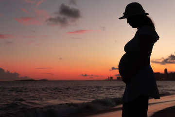 Fototapeta premium Silhouette of a pregnant woman on the beach at sunset. Vila Velha, ES, Brazil.