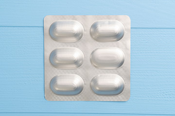 Blister pack of medical pills on a wooden blue background. The concept of alternative treatment for coronavirus
