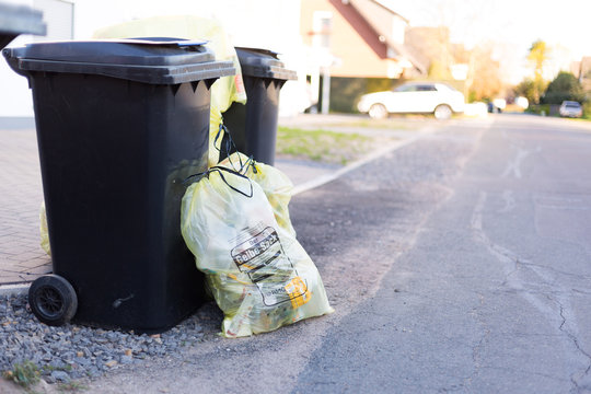 Plastiks&auml;cke und Altpapiertonne stehen am Stra&szlig;enrand