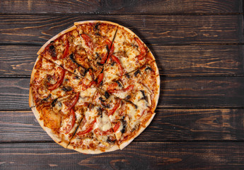 Pizza with mushrooms and chicken on a wooden table.