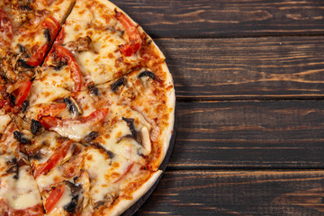 Pizza with mushrooms and chicken on a wooden table.