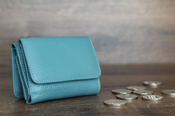Coins and wallet on a wooden background. Stack of coins. Coins are scattered on the table. Blue wallet.