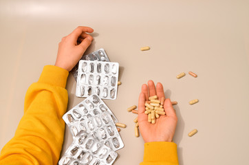 Obraz premium Hands with pharmaceuticals antibiotics pills medicine. colorful antibacterials pills on beige background. capsule pill medicine. Simbol of 2020 year, cronavirus broblem