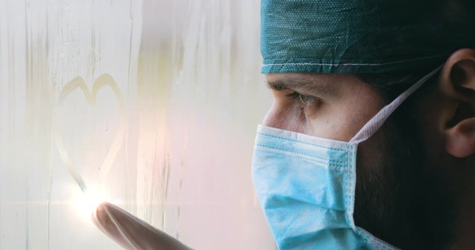 Medico disegna un cuore sul vetro appannato della finestra dell'ospedale