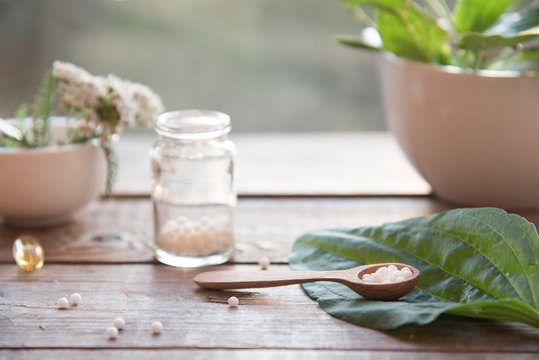 homeopathic granules, medicinal herbs on a natural wooden table on a natural background. alternative medicine and homeopathy