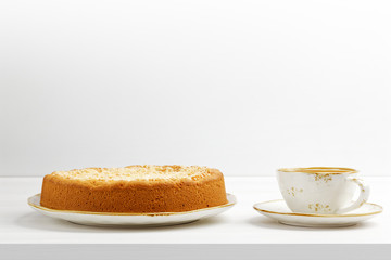 Closeup homemade cheesecake with streusel and cup of coffee on white wooden table. Front view. Copyspace.