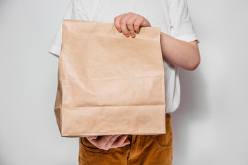 Brown craft paper bag for the removal or delivery of goods and food in hands on a white background. Place for advertising. delivery service concept