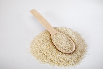 Grits rice in a wooden spoon, background. Rice background