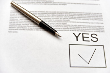 contract form with signature approval yes. ink pen lies on paper