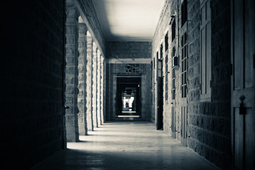 A monochrome picture of a long dark corridor in an old building
