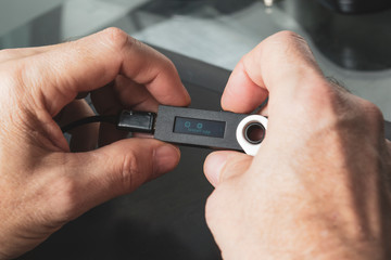 A close up of a man's hands holding a hardware wallet and starting the set up process