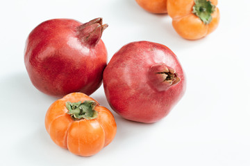 Fototapeta na wymiar two ripe bright red pomegranates and persimmon