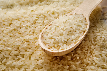 Grits rice in a wooden spoon, background. Rice background