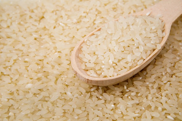 Grits rice in a wooden spoon, background. Rice background