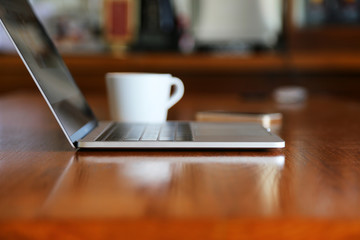 Laptop with a cup of hot coffee and smartphone on wooden table, Working remotely.