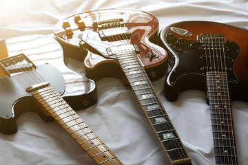 Three electric guitars placed on a white cloth, for sing a song, macro abstract