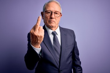 Grey haired senior business man wearing glasses and elegant suit and tie over purple background...