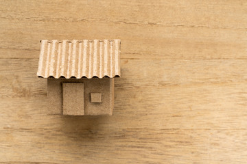 Model of cardboard house isolated on wooden background for building, mortgage, real estate or buying a new home concept. Lay flat view.