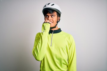 Young handsome cyclist man wearing security bike helmet over isolated white background looking stressed and nervous with hands on mouth biting nails. Anxiety problem.