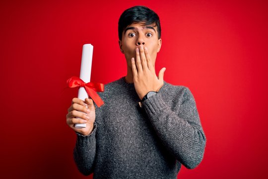 Young student man holding university graduated diploma degree over red background cover mouth with hand shocked with shame for mistake, expression of fear, scared in silence, secret concept