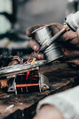 An electrician or repairman connects the electric wires of the motorcycle during the repair of motorcycle spare parts.