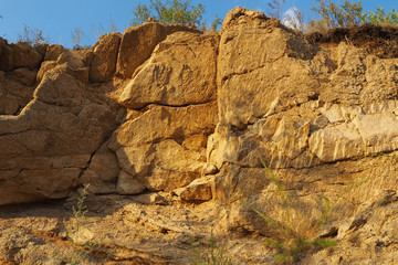 The yellow fantastic rock with cracks, the blue clean sky in the summer evening.