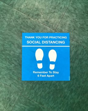 Thank you for practicing social distancing sticker is on the floor of a local business 