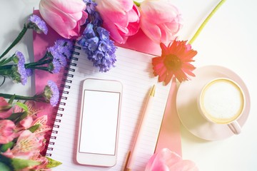 Obraz na płótnie Canvas Pretty Styled Desktop with mockup smartphone on notebook with pink spring flowers and cup of coffee on white background. Blank screen, copy space. Home office. Female. Feminine design