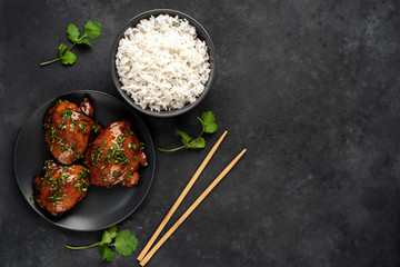 grilled sweet chicken thighs and  cooked rice on a stone background 
with copy space for your text. Asian food
