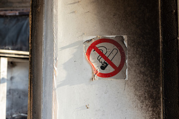 molten sticker with a no smoking sign on the wall with traces of black soot from a fire....