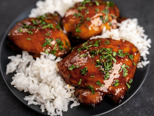 grilled sweet chicken thighs and  cooked rice on a stone background 
 Asian food