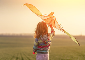 Little girl holding kite at sunset