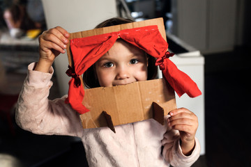 Caucasian girl child plays in a cardboard theater - obrazy, fototapety, plakaty