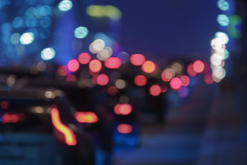 Defocused photography of Moscow cityscape in night time. Big traffic. Street is filled with cars. Blurred motion of cars at motorway. Illuminated buildings. Back / rear view.
