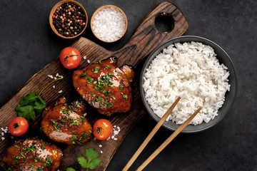 grilled sweet chicken thighs and  cooked rice on a stone background 
 Asian food