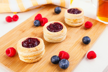 Danish pastry cake with cranberry jam and fresh blueberry and raspberry on the table. Sunny breakfast.